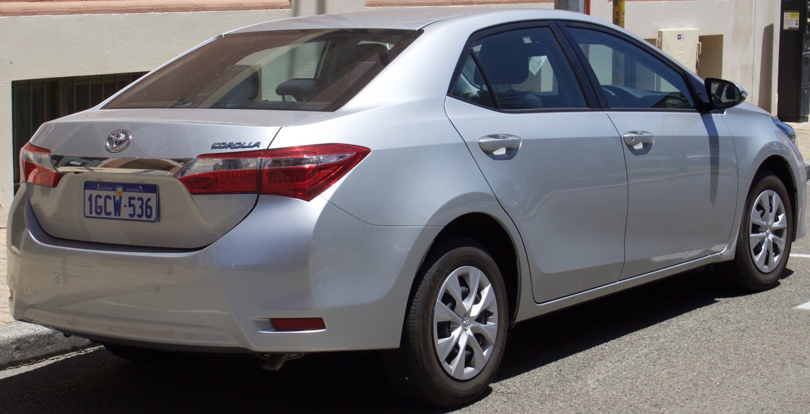 Silver Toyota Camry sedan parked on a city street, rear and side view showing license plate 1GCW-536 (Western Australia).