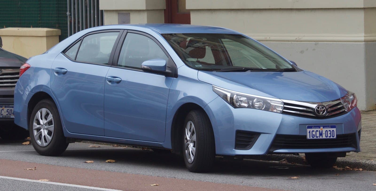 Blue Toyota sedan parked on the street, front-right view, license plate visible (1GCM-030).