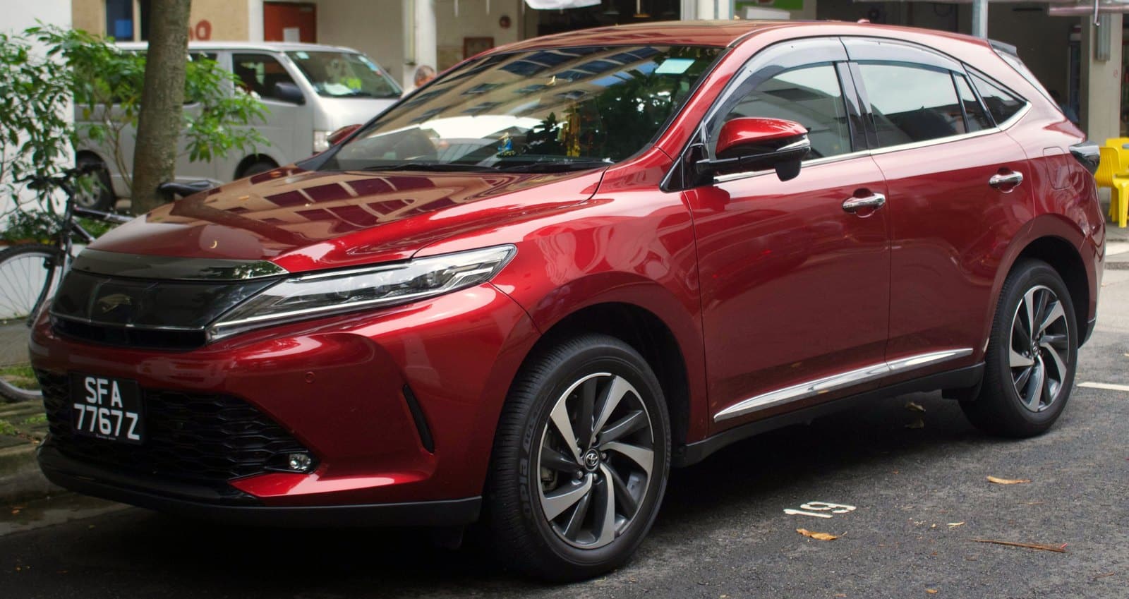 Front three-quarter view of a shiny red SUV parked along a curb, license plate SFA 776Z visible