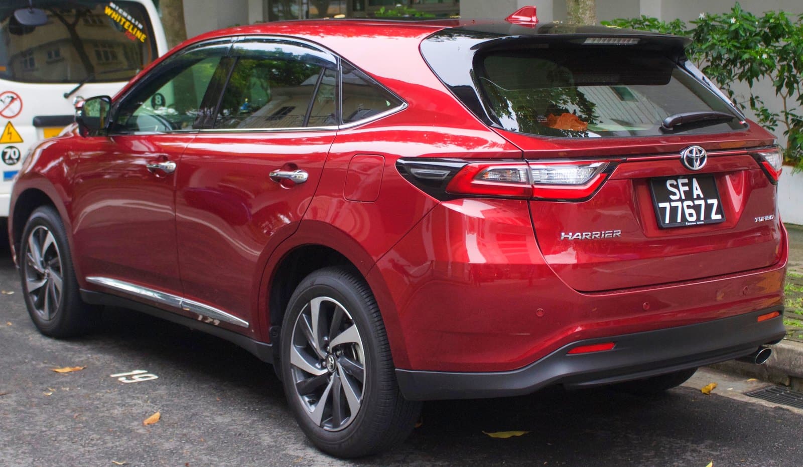 Red Toyota Harrier parked on a street, showing the rear three-quarter view and license plate SFA 7767Z.