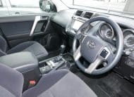 Interior of a car showing the driver's seat, steering wheel, center console, and dashboard controls as seen from the passenger side perspective.