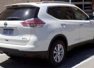 White Nissan Murano SUV shown from the rear-three-quarters, parked in a parking lot with a storefront and pedestrians in the background.