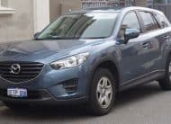 Blue Mazda SUV parked on a street, front-left angle, with license plate visible (Australia).