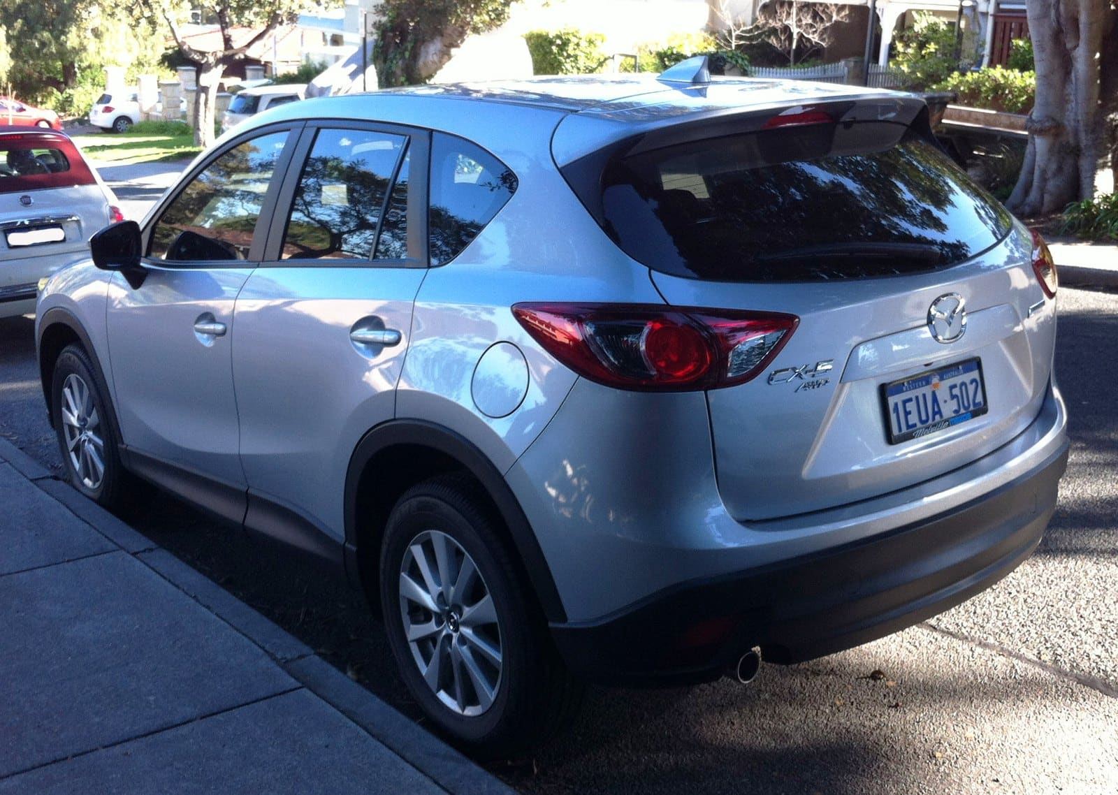 Silver Mazda CX-9 parked on a residential street, rear three-quarter view, license plate TEUA-502 visible.